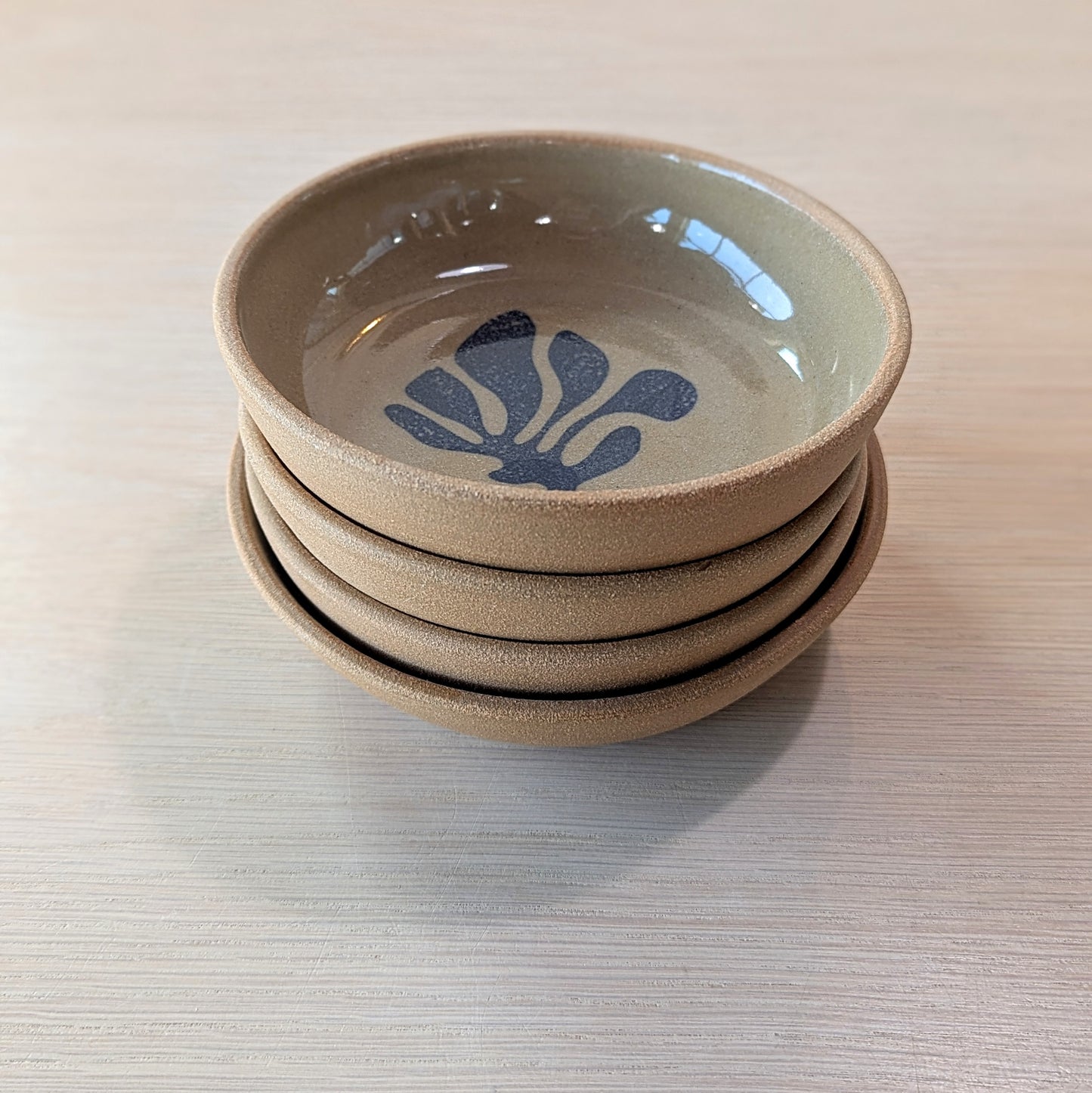 Stack of ceramic bowls with a blue floral design on a light wooden surface