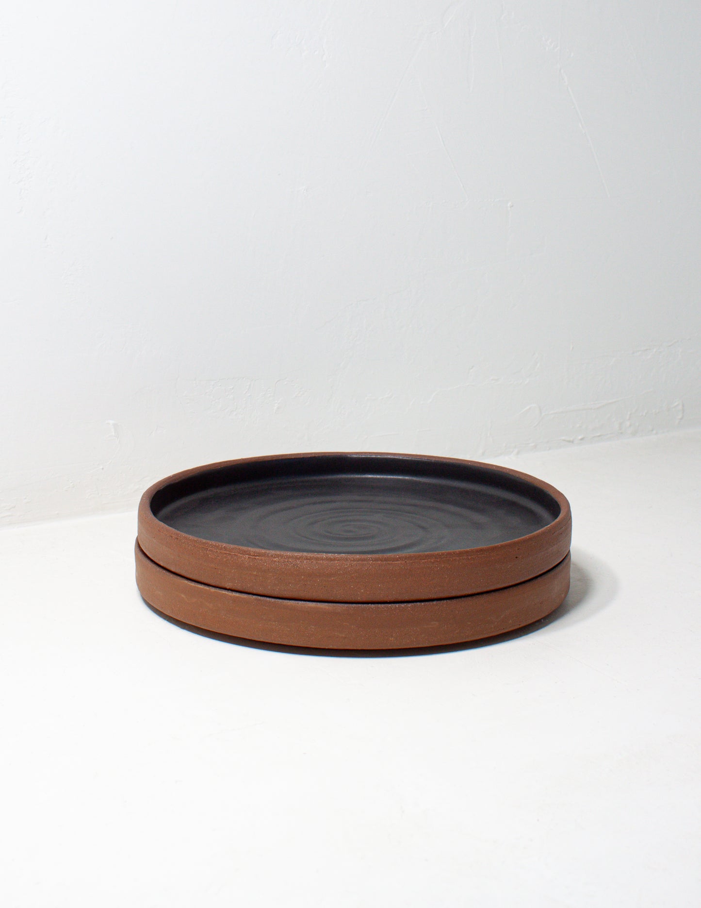 A stack of two modern handmade share plates glazed in black