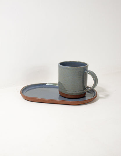 handmade ceramic serving platter with a handmade mug sitting on top