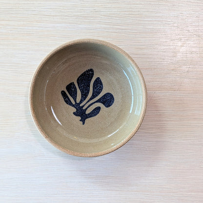 handmade bowl with a blue leaf design on a light ceramic surface