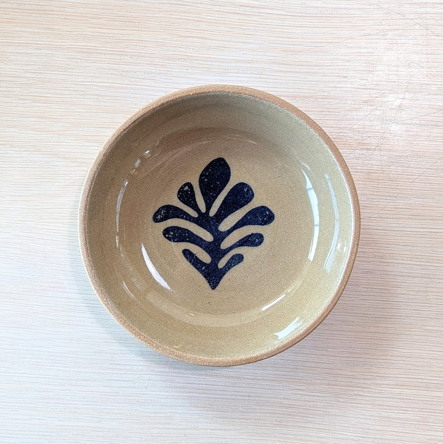 handmade bowl with a blue leaf design on a light ceramic surface