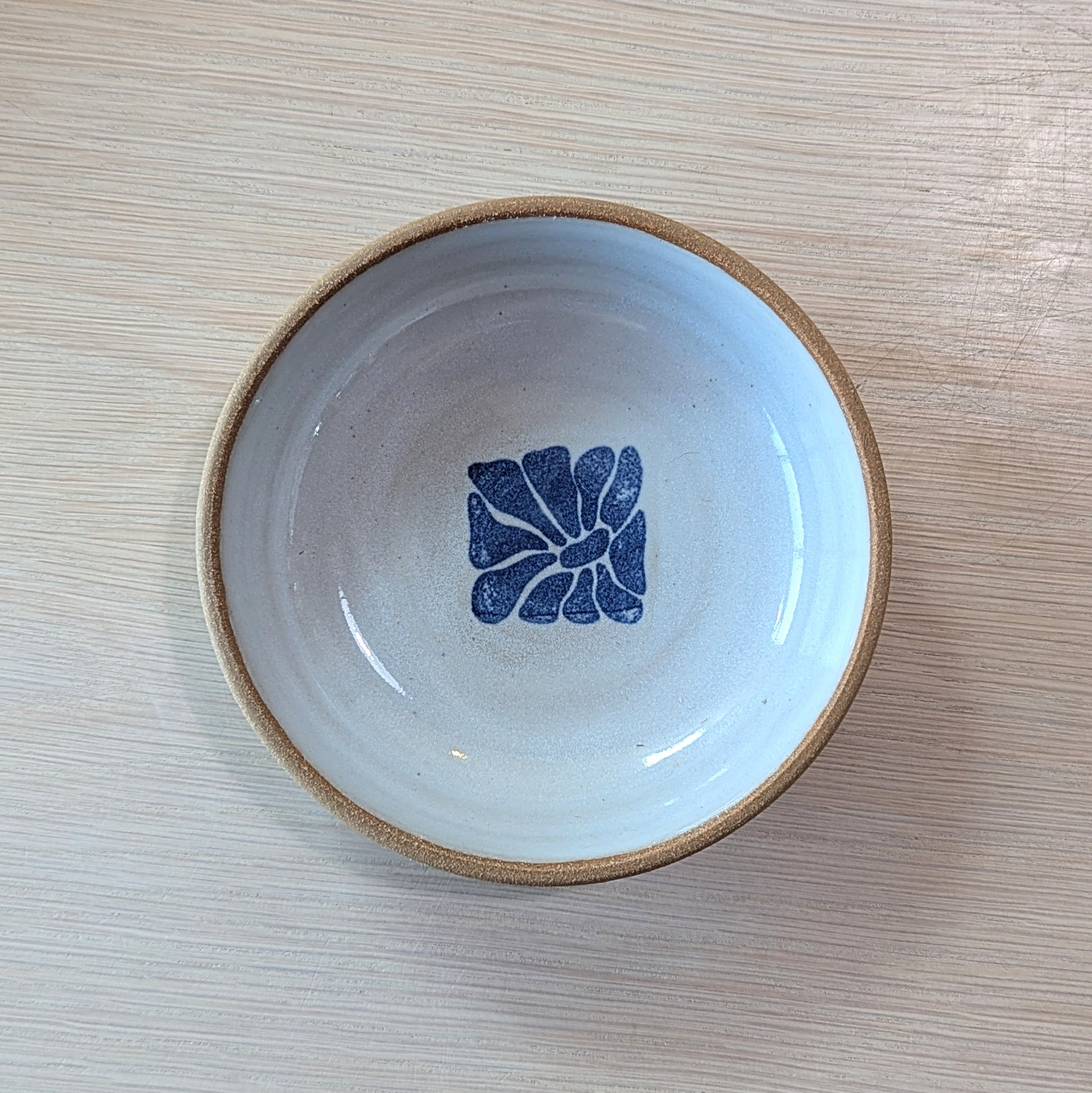 handmade bowl with a blue floral design on a white ceramic surface
