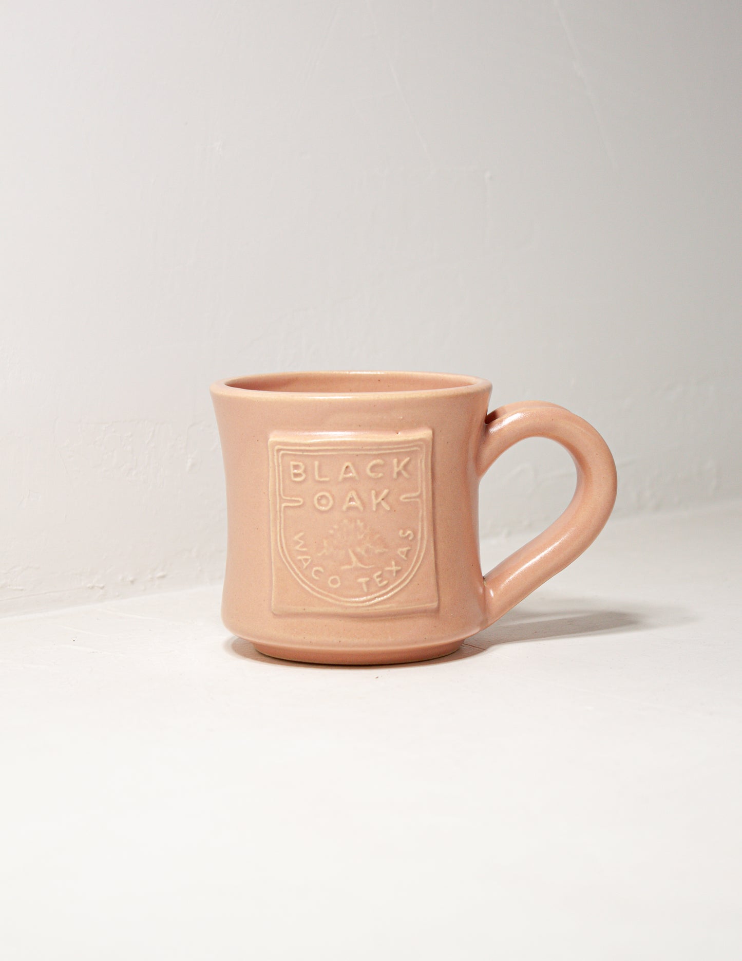 Hand thrown coffee mug in standard shape with matte coral glaze